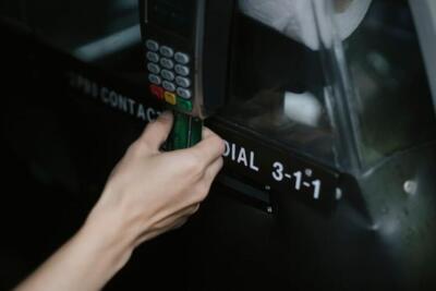 Crop anonymous traveler using card device while paying for taxi ride in automobile