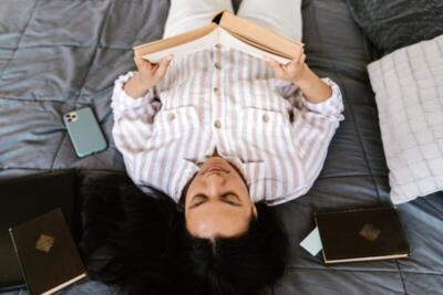 Young woman lying on bed, enjoying a book during leisure time.