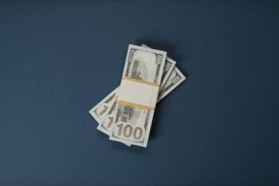 Stack of 100 US dollar bills on a dark surface, symbolizing wealth and finance.