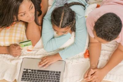 Mother and children shopping online together at home on a laptop.