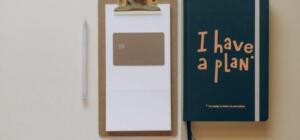 A minimalist office setup featuring a planner, clipboard, card, and pen, perfect for planning and organization.