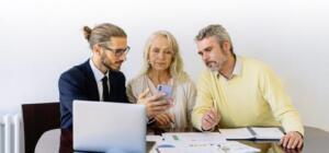 Three individuals collaborating on financial documents during a business meeting.