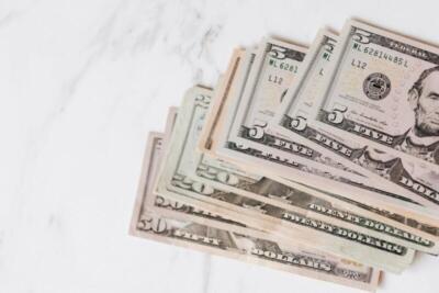 Close-up shot of various US dollar bills on a marble tabletop, showcasing finance and wealth.
