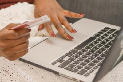 A person uses a credit card for online shopping on a laptop, highlighting digital convenience.